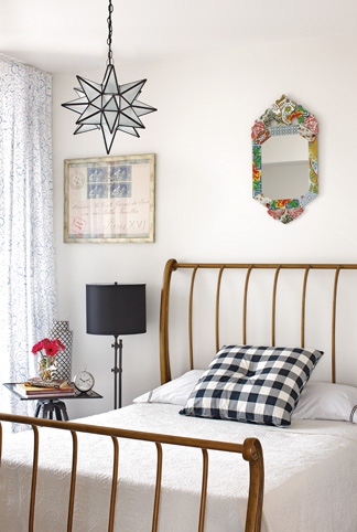 Bedroom with wire frame bed, gingham accent pillow, a small mirror above the metal headboard and a star pendant light