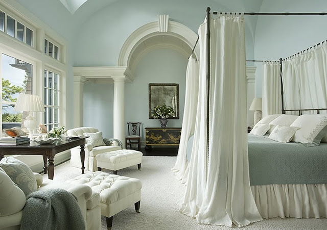 Blue bed room in a South Carolina estate with a canopy bed and white armchairs with matching ottomans