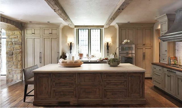 Large kitchen with a huge island with reclaimed wood cabinets and counter height bench seating. The rest of the kitchen has reclaimed wood cabinets, exposed beams and a wood floor