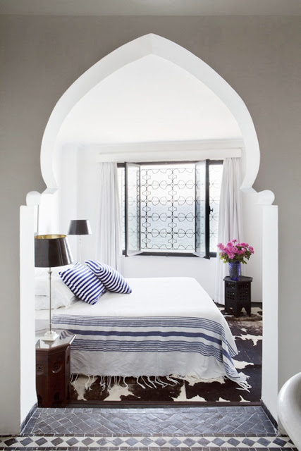 morrocan bedroom with doorway arch, tiles, iron on the window and an animal print rug