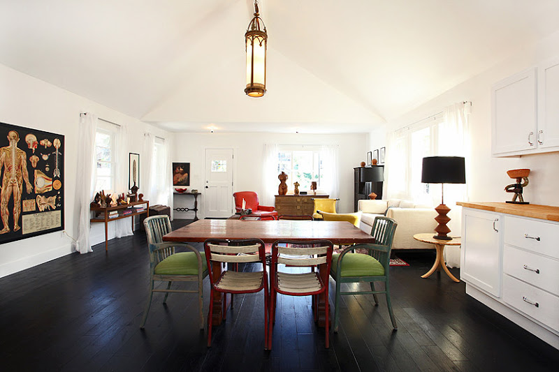 Dining room with stained wood floor, wood table, mismatched chairs, a pendant light and an anatomy poster