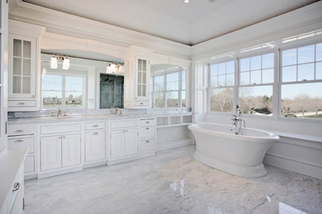 large white master bathroom with lots of widows, white cabinets and a stand alone tub