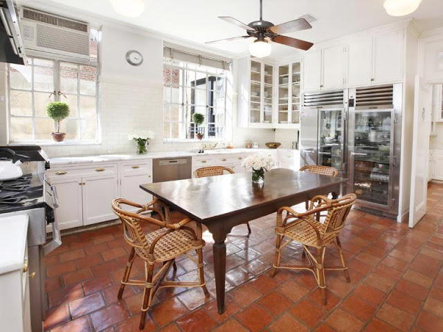 kitchen in an apartment with Saltillo tiled floors, traditional white cabinetry, subway tile backsplash, stainless appliances and glass front refrigerator.