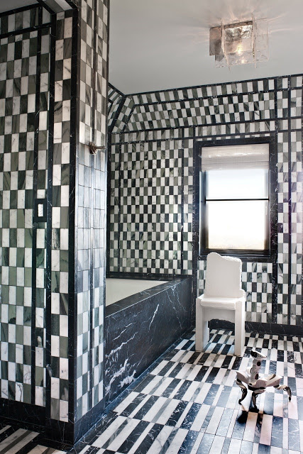 Black and white marble floor to ceiling bathroom tile and a small robot