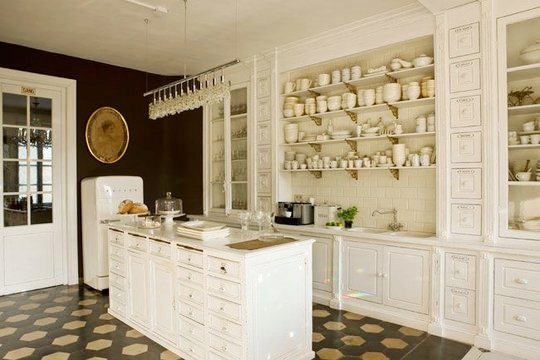 Kitchen with terra cotta floors, white shop counter, white open shelving, and white subway tile backsplash in a mansion in Belgium
