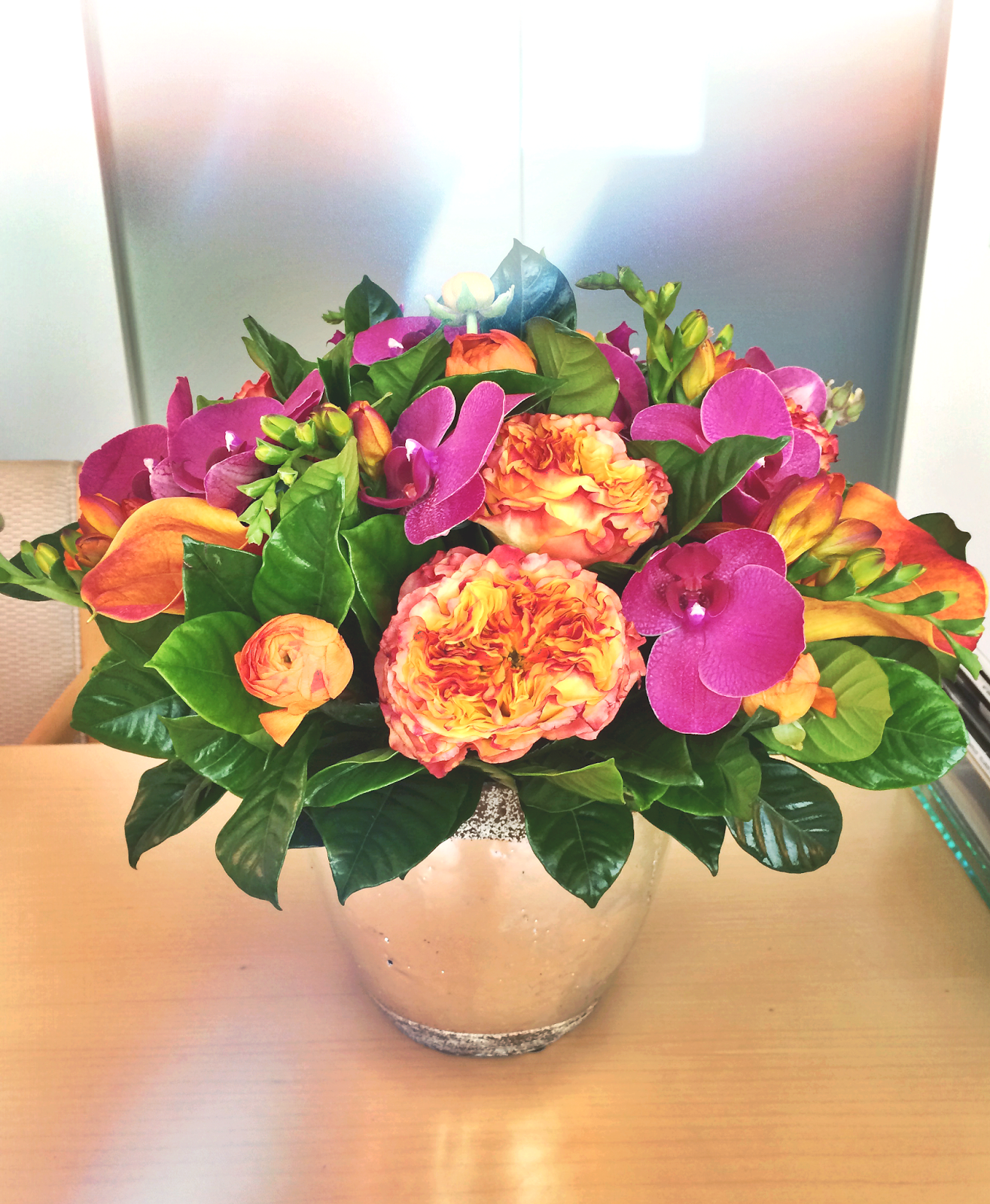 Fall floral arrangement with orange ranunculus, calla lilies and fresia with purple orchids