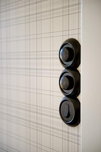 plaid wallpaper with dark brass light switches