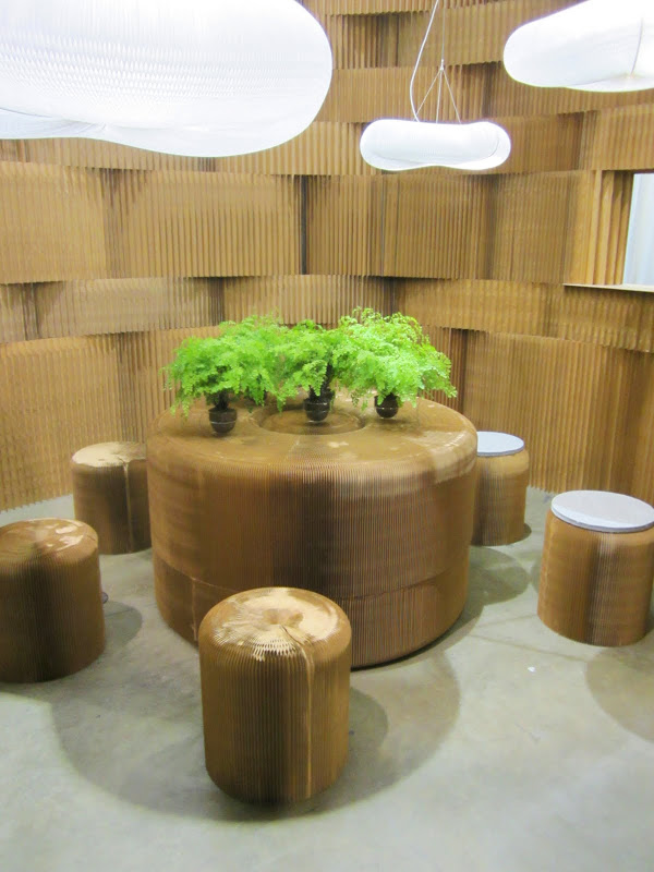 Room with a round table, five stools and a textured wall made out of kraft paper