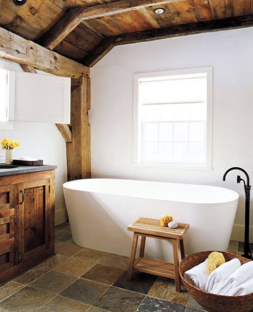 Master bathroom with modern stand alone tub, stone floors, exposed beams and reclaimed wood cabinets and drawers