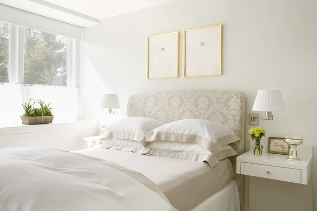 Bedroom with a white upholstered headboard, large window and a white nightstand with a floating drawer