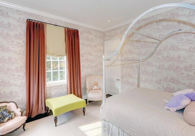 Girl's room with a canopy bed, toile wallpaper, yellow bench window seat and coral floor length curtains