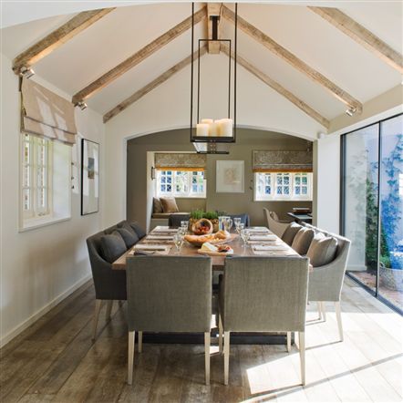 Dining room with glass wall sliding door, reclaimed wood floor, exposed beams, a chandelier and grey upholstered chairs