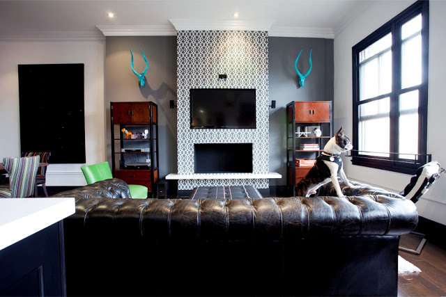 Living room in Daniel Lowe's Hollywood loft with tufted leather couch and trellis fretwork gray wallpaper on on the fireplace 