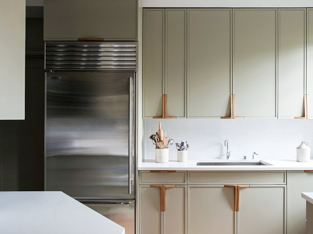 Close up of the greige cabinets and their L shaped wood door handles in the kitchen
