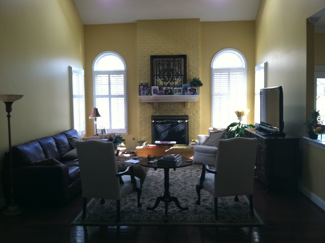 yellow family room with yellow painted brick fireplace, a sofa, two armchairs and a chest of drawers