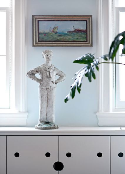 concrete sailor satatue sitting on top of a light gray cabinet with finger holes to open