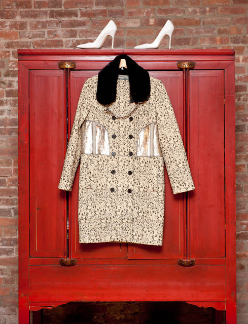 Red wardrobe in front of a brick wall with a pair of white heels on top and a jacket with fur trim hanging on the front