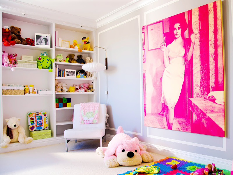 Girls room in Diego Garcia's NYC apartment with built in bookshelves, white armchair, a lantern lamp, a bright colored rug and over sized stuffed dog and a wall sized mural of Elizabeth Taylor