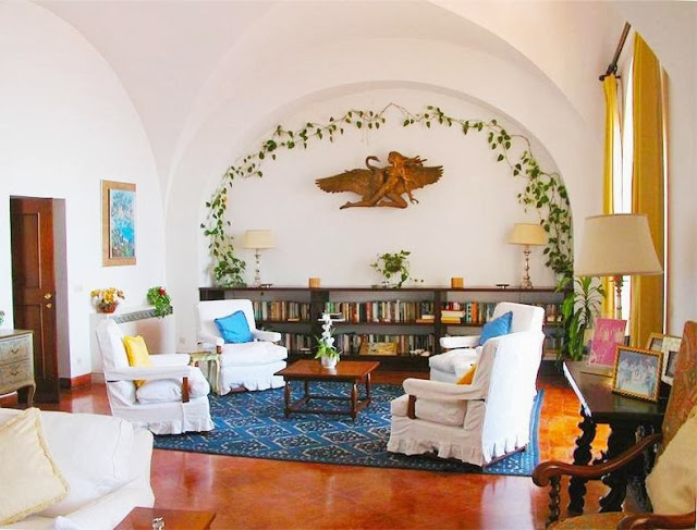 Library in Castiglione castle in Capri with wood floor, white armchairs, arched ceiling and ivy on the wall