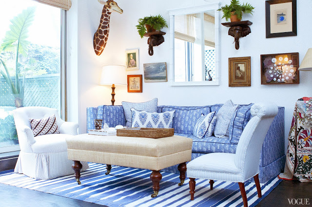 Blue and white living room in Rebecca de Ravenel's New York apartment with a blue and white sofa, white armchair, blue and white striped rug and an ottoman style coffee table