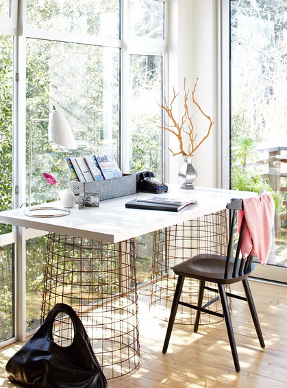 home office with large windows overlooking a backyard, wood floors and a desk with a white top with wire drums holding it up