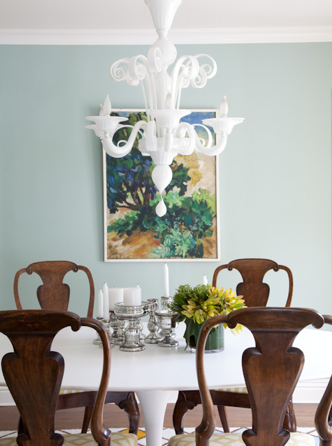 Opaque white Murano glass chandelier in a dining room with wood chairs around a white table and mint walls