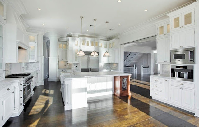 kitchen with hardwood floors, white marble counters, stainless steel appliances, white cabinets and a huge island with pendant lights