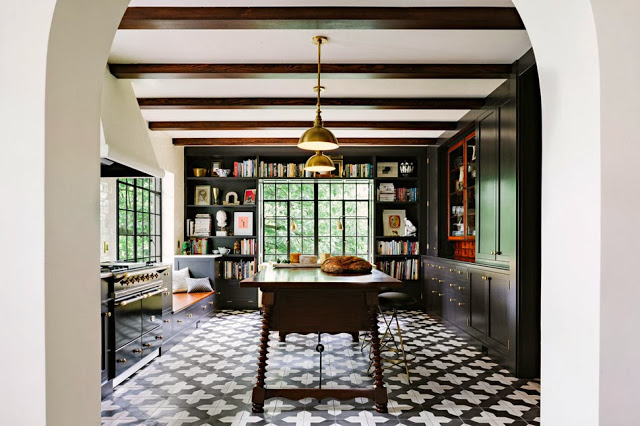 Modern kitchen with cement tiles, brass accents, black cabinets, subway tile backsplash and built in bookshelves