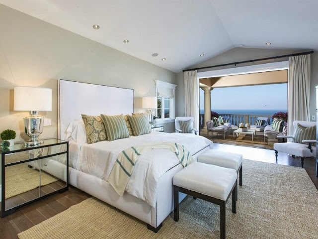 Bedroom in a Malibu villa with mirrored night stand and lamp and tall white headboard