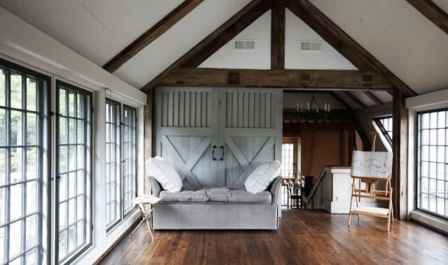 Yoga studio with hardwood floors, large paned windows, exposed beams, and a sliding barn door