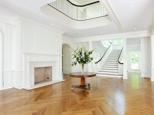 foyer with white grand staircase, fire place and herringbone wood floor