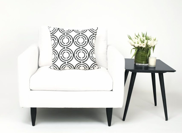 COCOCOZY Light Pillow in black and white on a white armchair with a black accent table, flowers and a candle