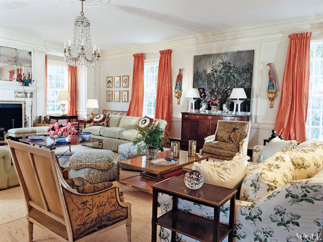 Living room with coral needlepoint louis XVI chairs, botanical printed sofa, coral curtains and a crystal chandelier