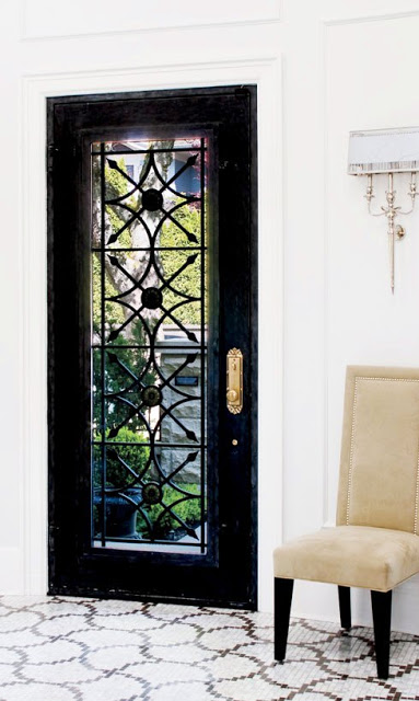 glossy black front door, marble mosaic tiles and a high back neutral chair with dark legs