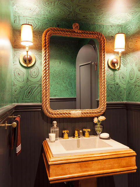 powder room with malachite inspired wallpaper, mirror with rope frame and matching gold wall mounted lamps