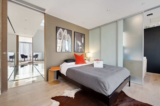 guest bedroom with animal skin rug, sliding door, wooden bed frame and orange accents