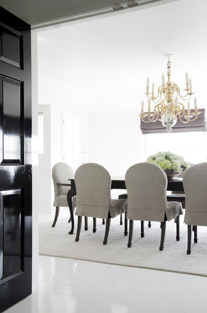 dinning room with black glossy doors, a gold chandelier, a dark wood table and gray chairs