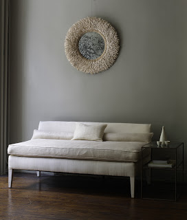 Grey sitting room vignette with a round mirror with a mohair frame and a white settee