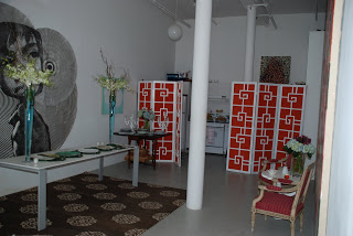Room in a NYC loft with red and white three panel screens, a brown and white rug and a large piece of wall art