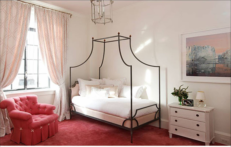 Girls bedroom by Peter Pennoyer with rose carpeting, an iron canopy bed and red tufted armchair