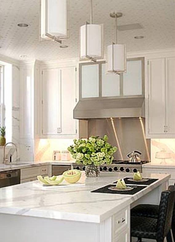 White kitchen by Peter Pennoyer with white marble countertops and backsplash, island with a bar and stainless appliances