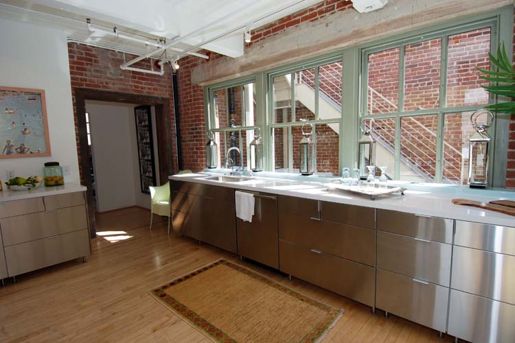 City loft kitchen in Los Angeles with exposed brick walls, mint green paned windows and sleek stainless cabinets