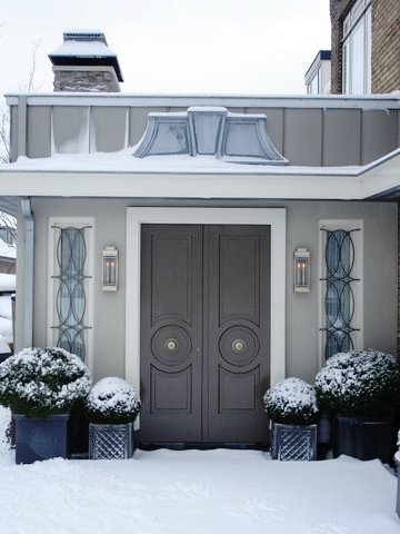 Carved glossy grey double doors with manicured hedges outside Ron van Empel of Empel Collections' home