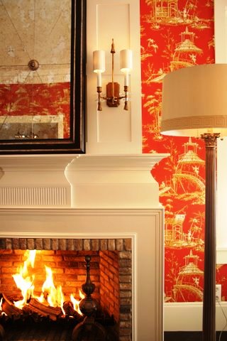 Ron van Empel of Empel Collections' home showroom with Red chinoiserie toile wallpaper around a white fireplace