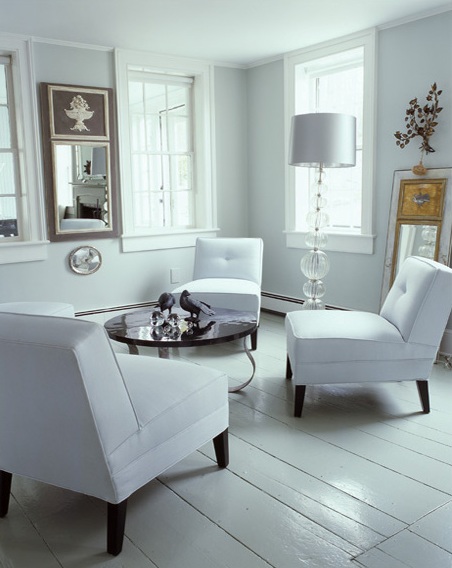 White living room with white washed wide planked floors, armchairs and a round coffee table