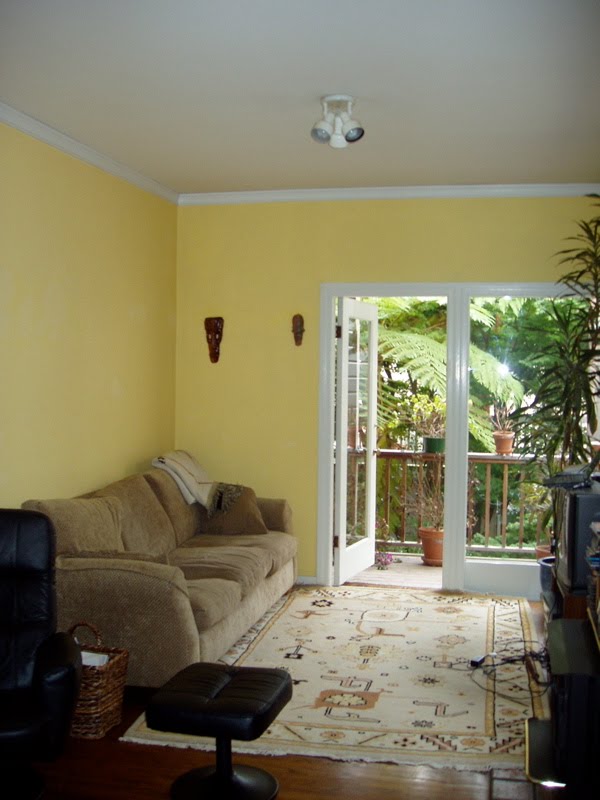 Living room before Niche Interiors' redesign with yellow walls, an Aztec rug and tan 1980s sofa