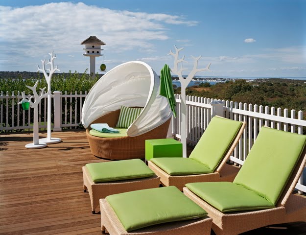 Outdoor patio with wicker lounge chairs with green cushions by Ghislaine Vinas 