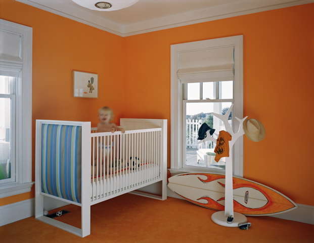 Orange nursery by Ghislaine Vinas with a white crib and a surfboard 