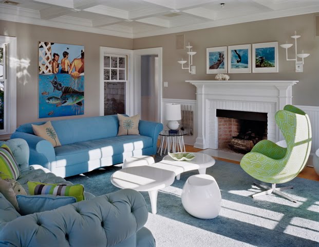 Living room by Ghislaine Vinas with light blue tufted Chesterfield sofa, modern white coffee table, classic Egg chair and a white fireplace