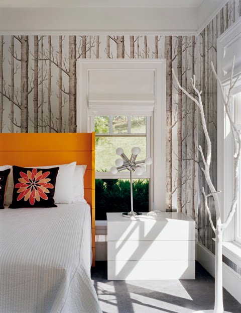 Guest bedroom by Ghislaine Vinas with branch wallpaper, orange hearboard and sleek white nightstand